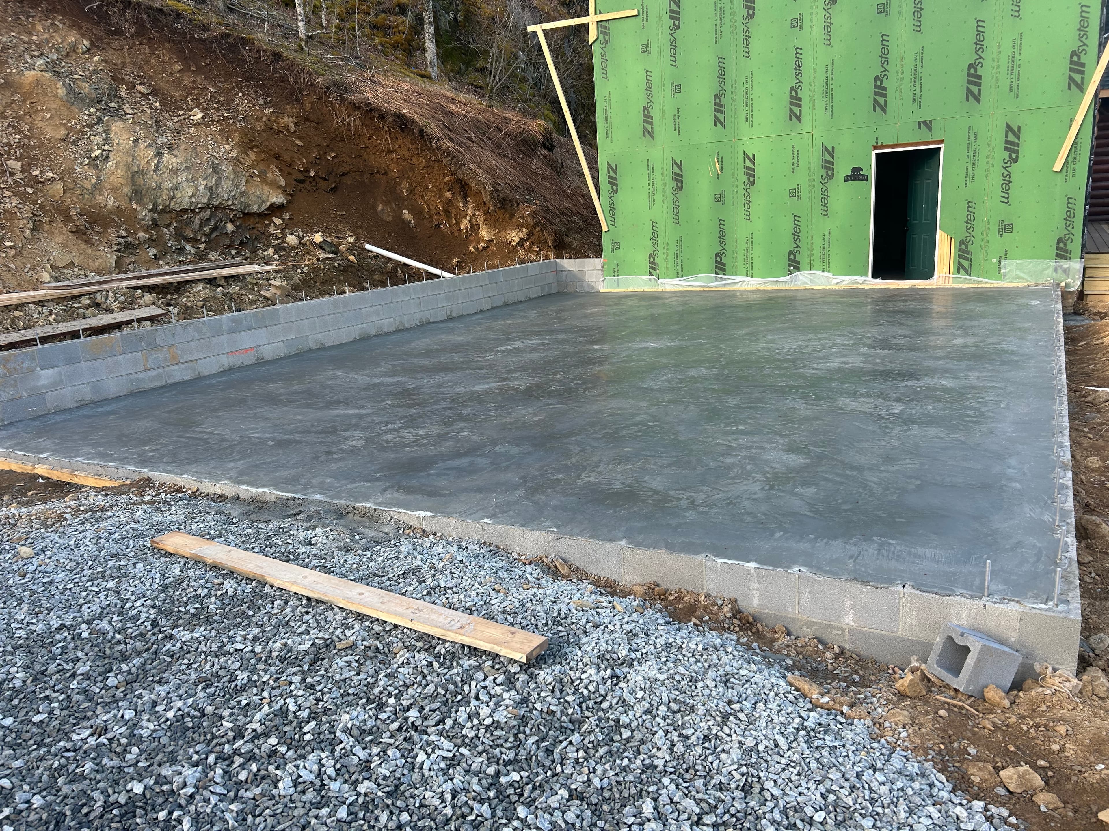 Fresh slab pour beside a new build foundation wall